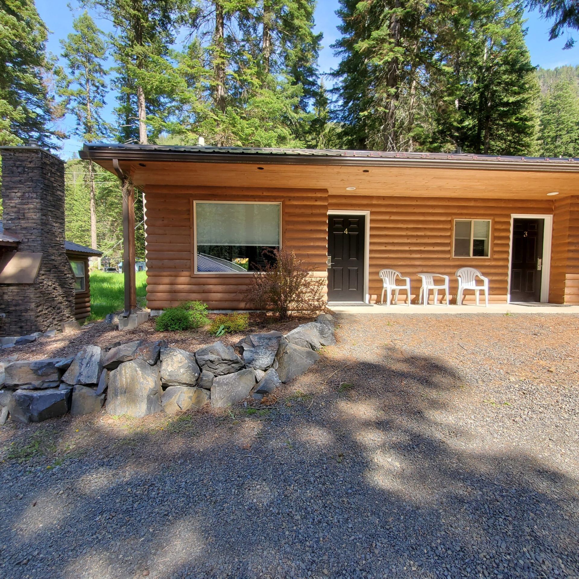 A log cabin with a fireplace and chairs in front of it