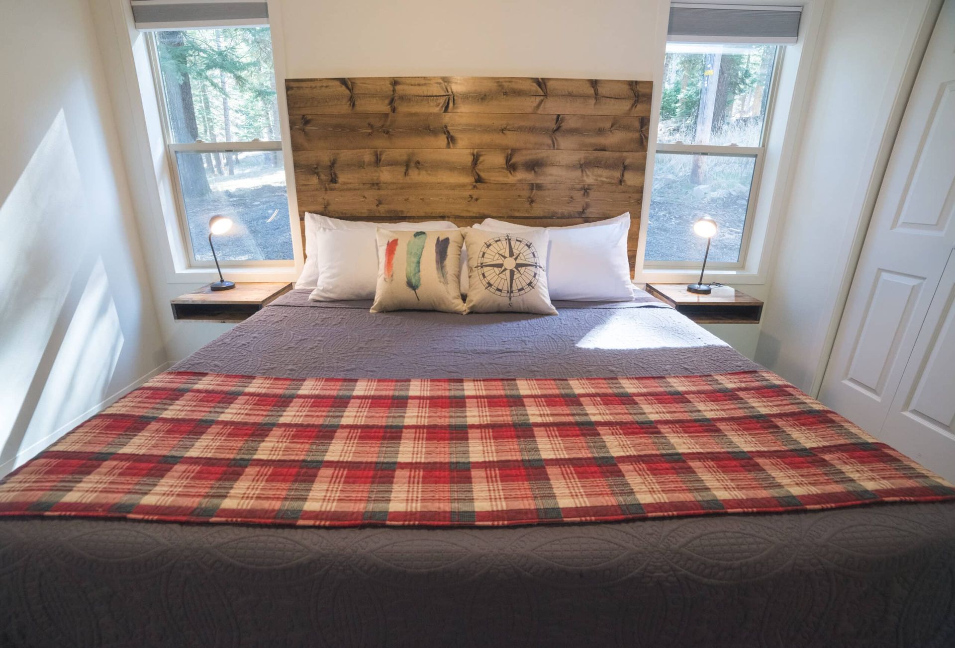 A bed with a wooden headboard and a plaid blanket in a bedroom.