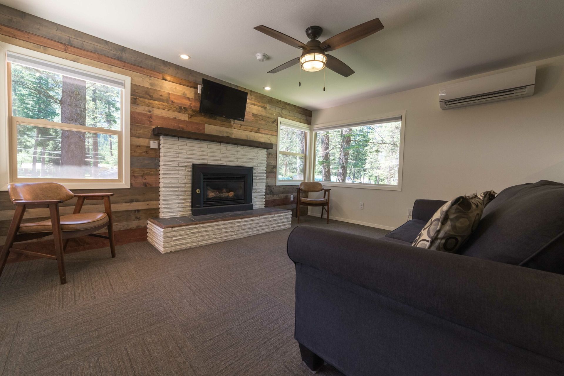 A living room with a couch , chair , fireplace and television.