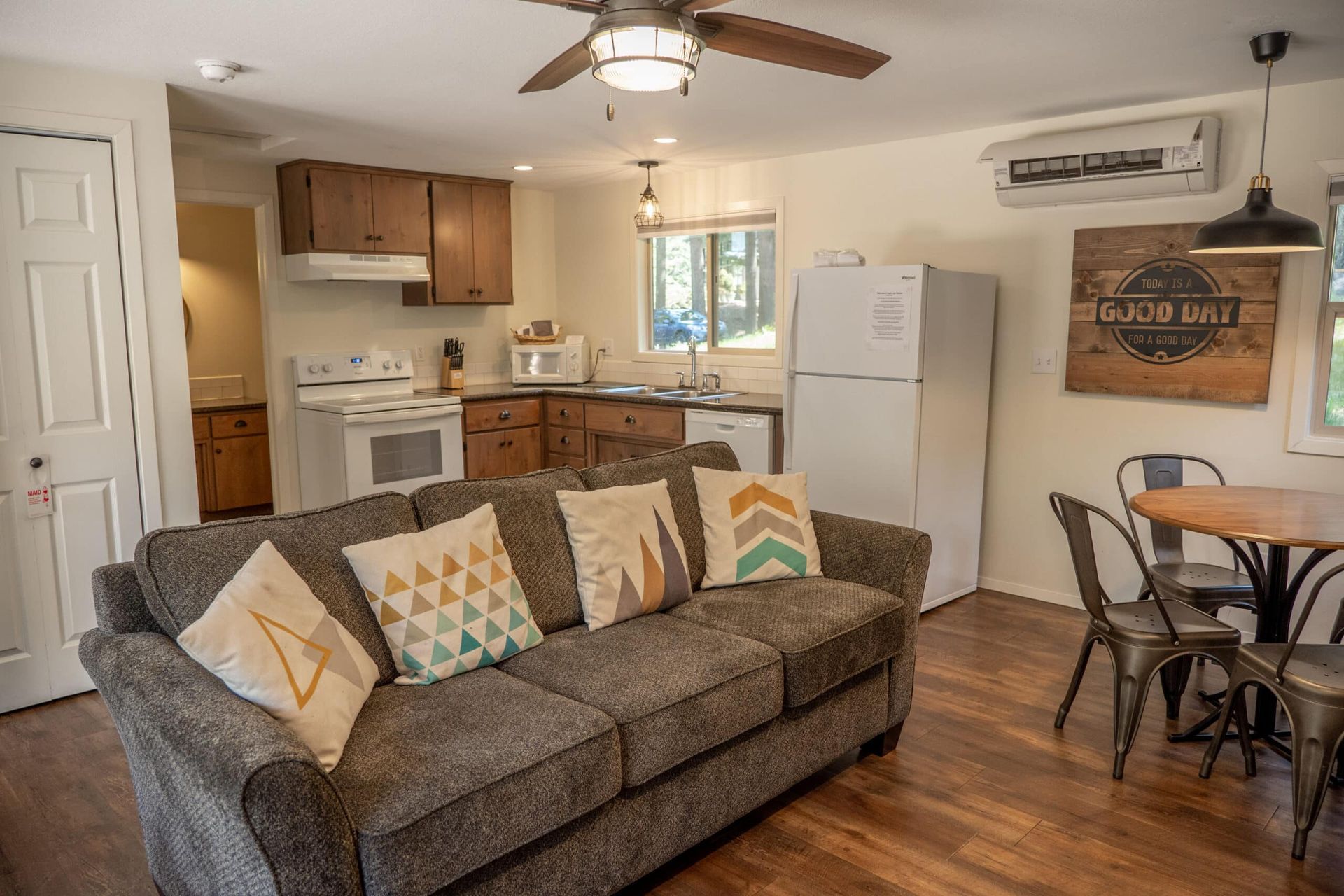 A living room with a couch , table , chairs and a ceiling fan.