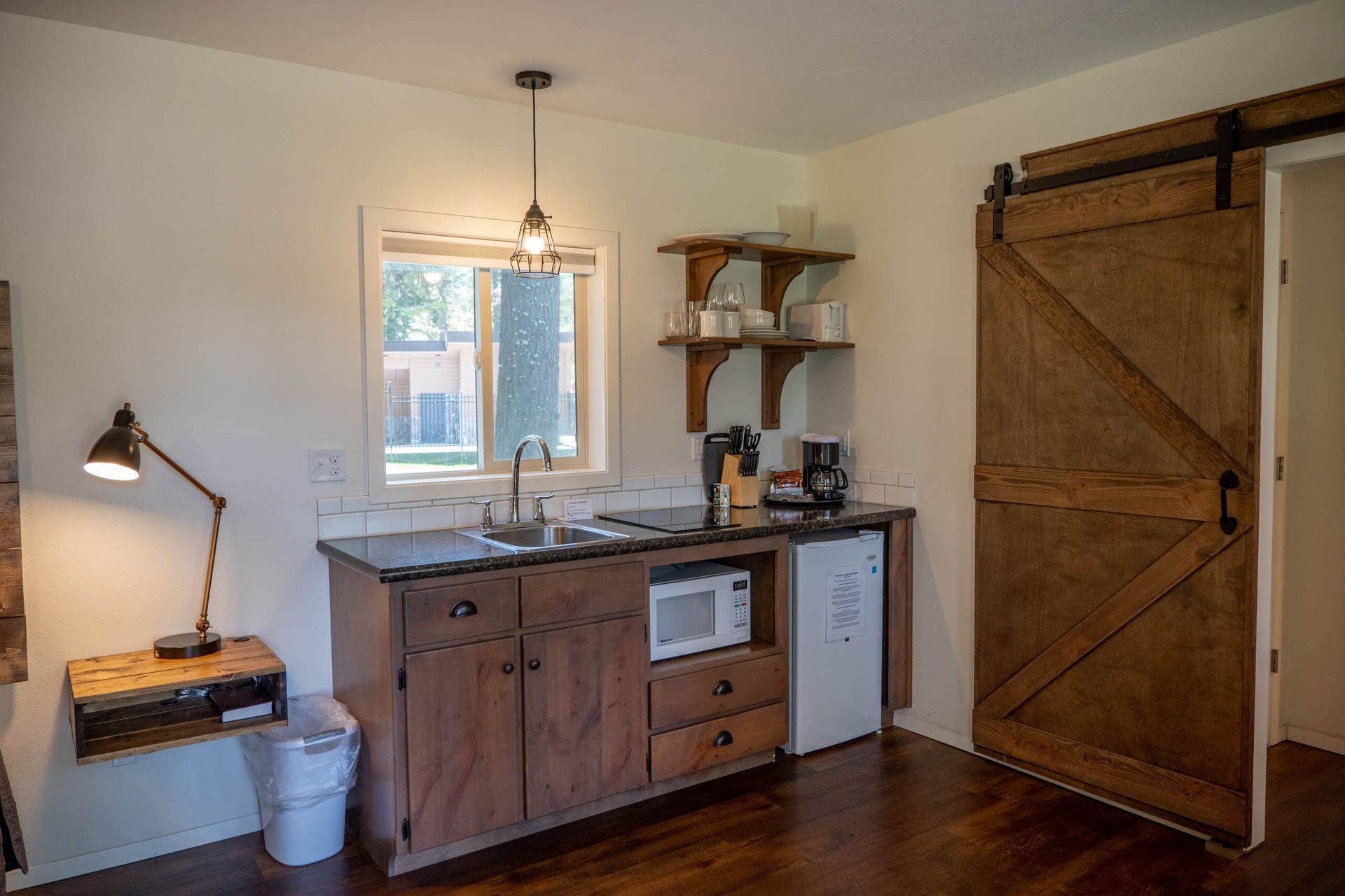 A kitchen with a sink , microwave , refrigerator and sliding barn door.