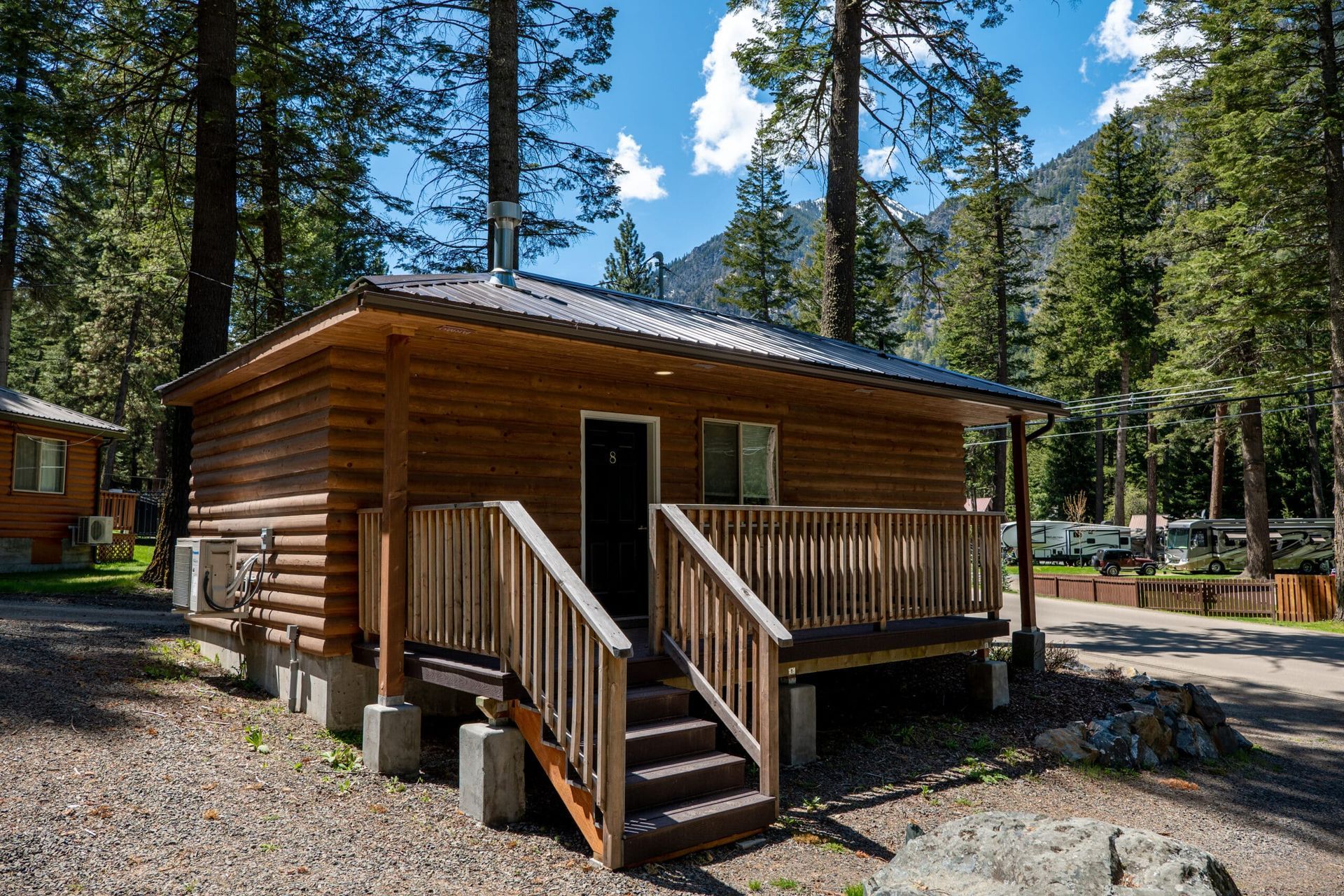 A small wooden cabin with stairs leading up to it is in the middle of a forest.