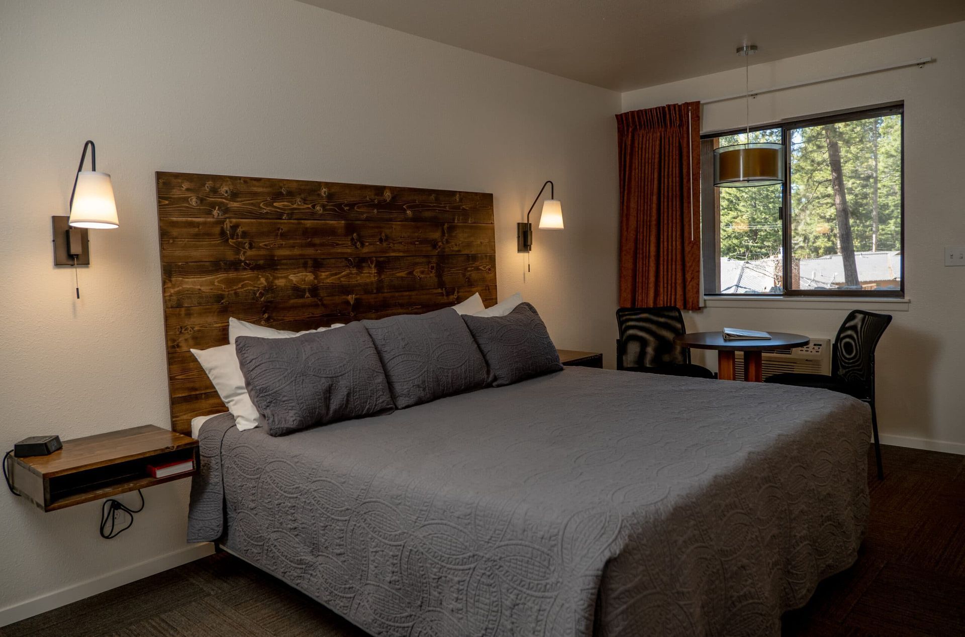 A hotel room with a king size bed , table and chairs.
