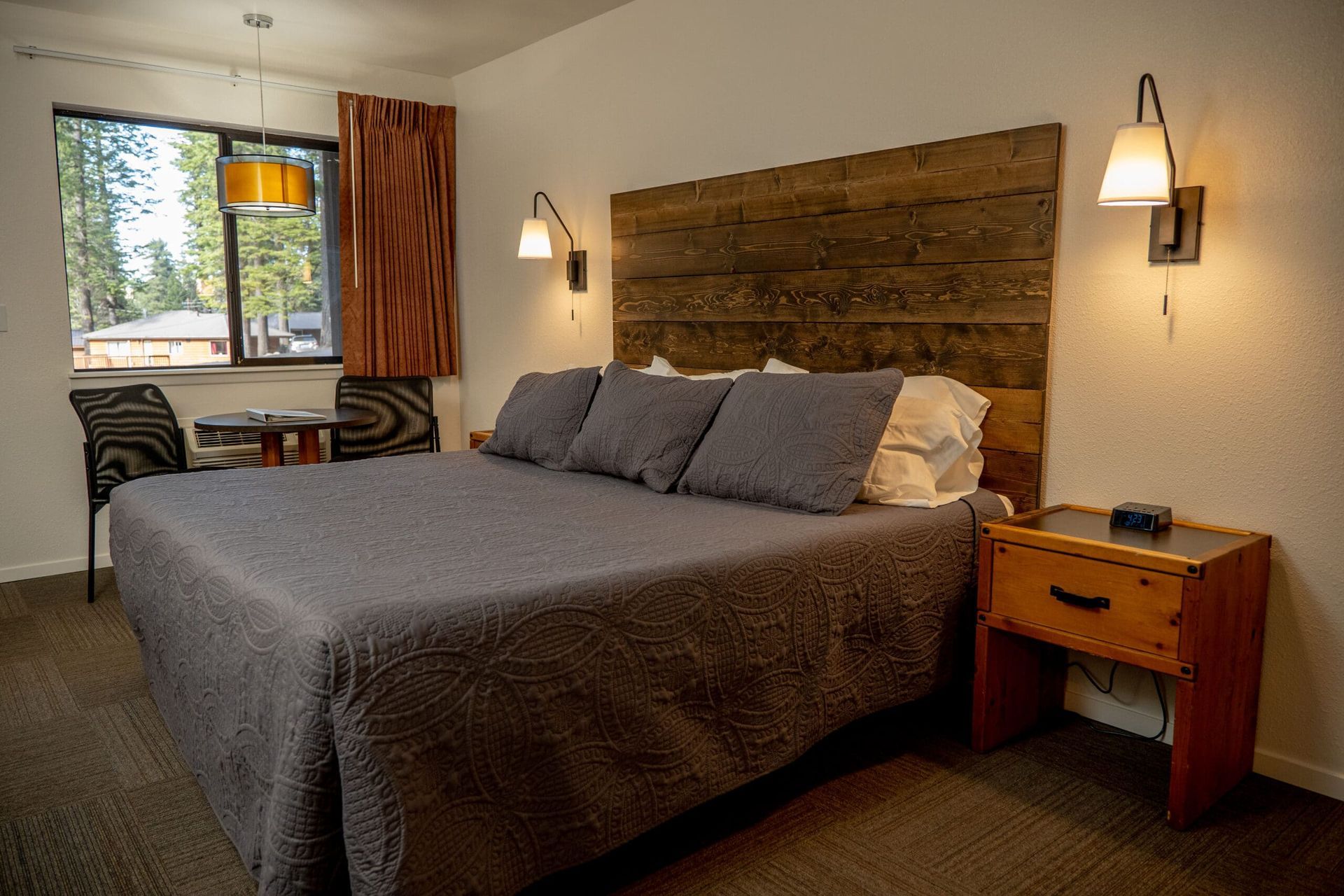 A hotel room with a king size bed and a wooden headboard.