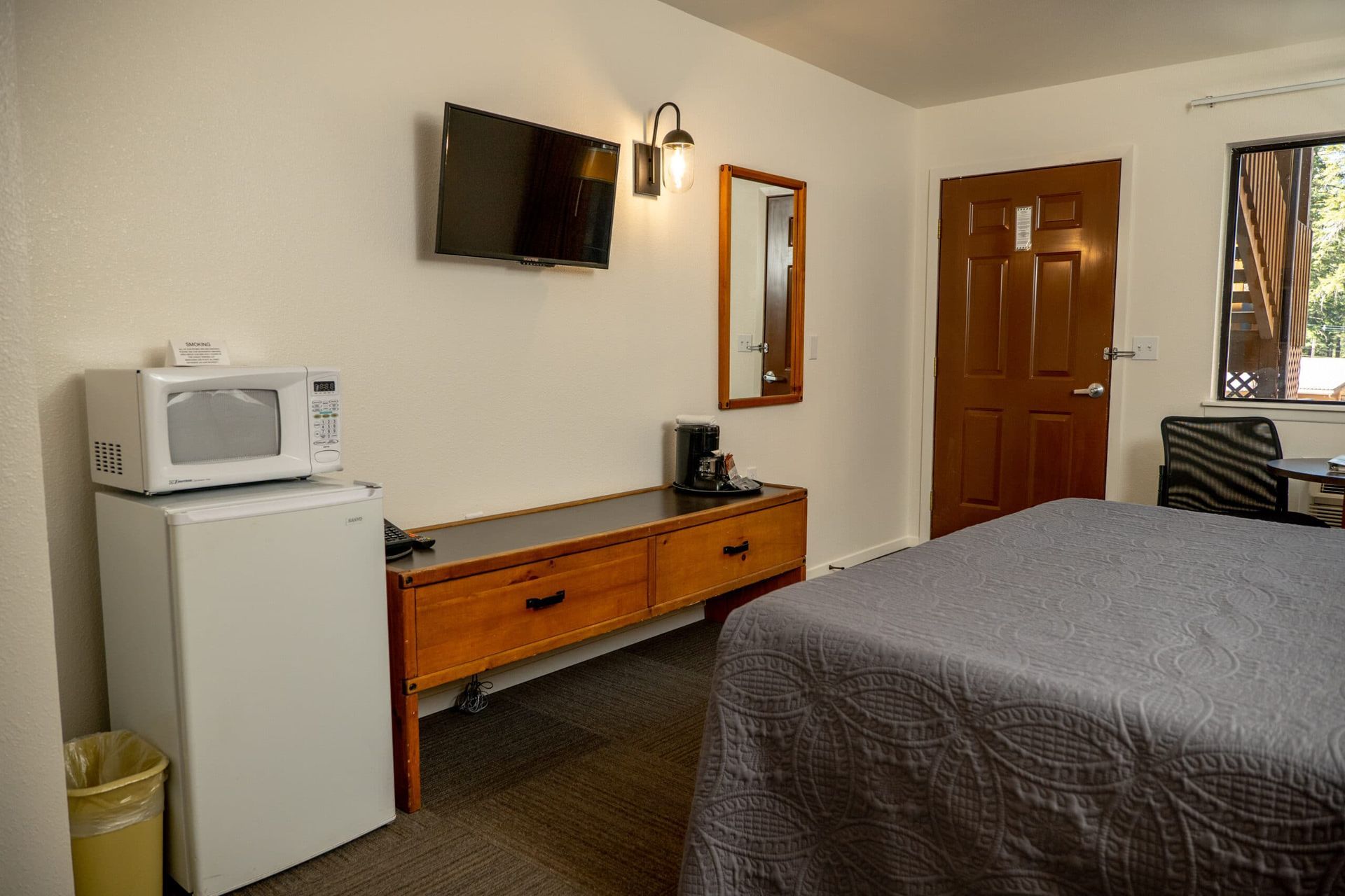 A hotel room with a bed , microwave , refrigerator and television.