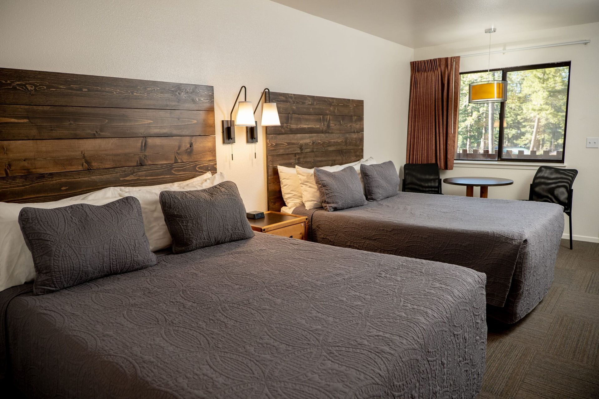 A hotel room with two beds , a table and a window.