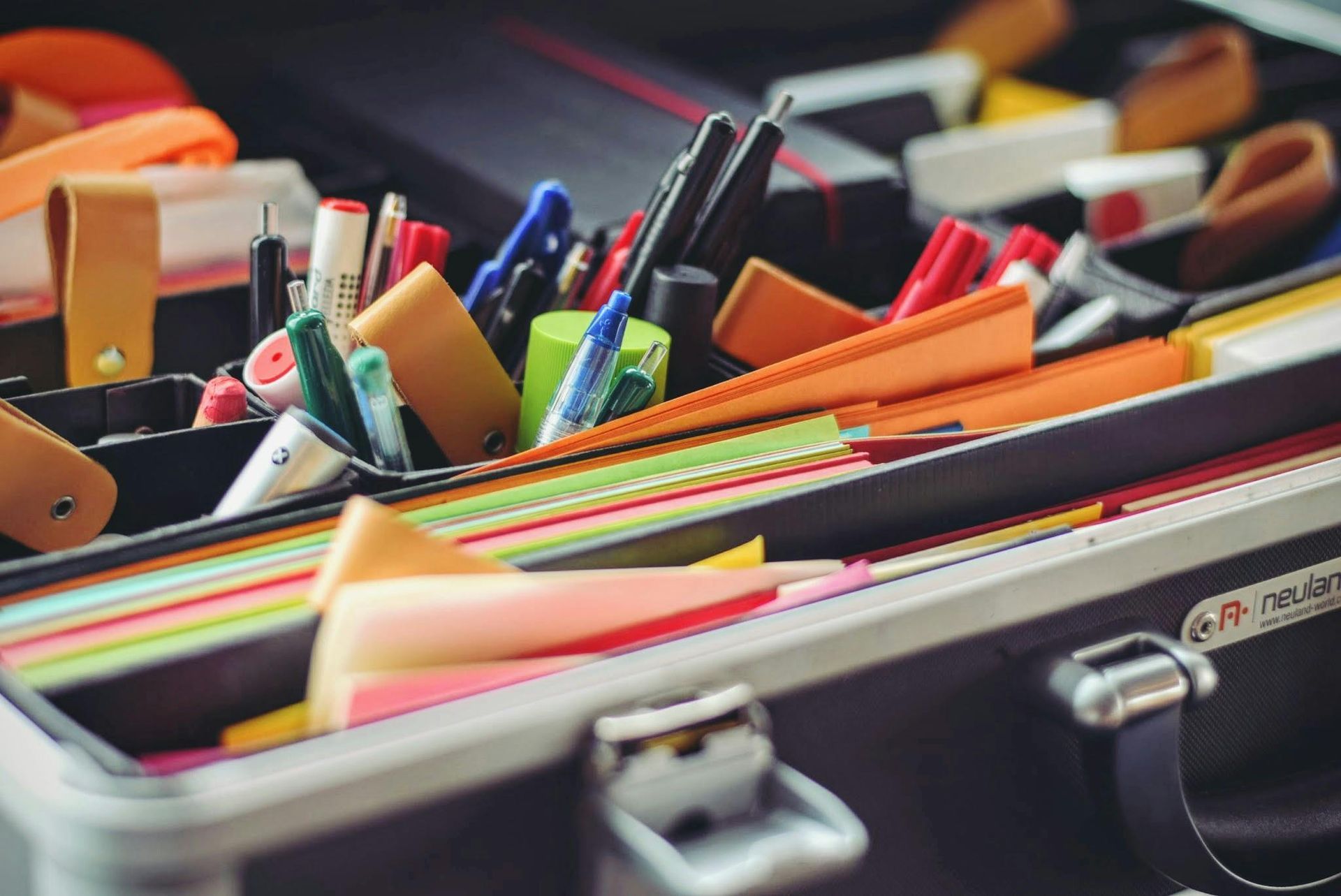 A briefcase filled with a variety of office supplies.