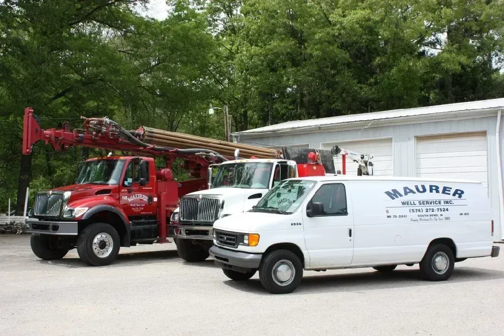 Three trucks and a van are parked in front of a building that says maurer Three trucks and a van are parked in front of a building that says maurer