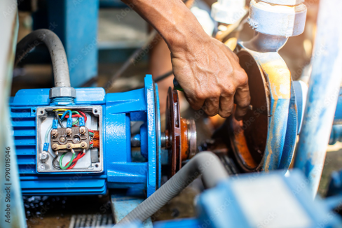 Technician repairing industrial pump system, adjusting motor coupling.