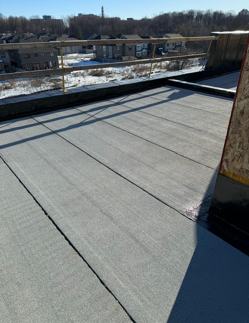 Snow-dusted flat rooftop with long shadows and a winter landscape in the distance