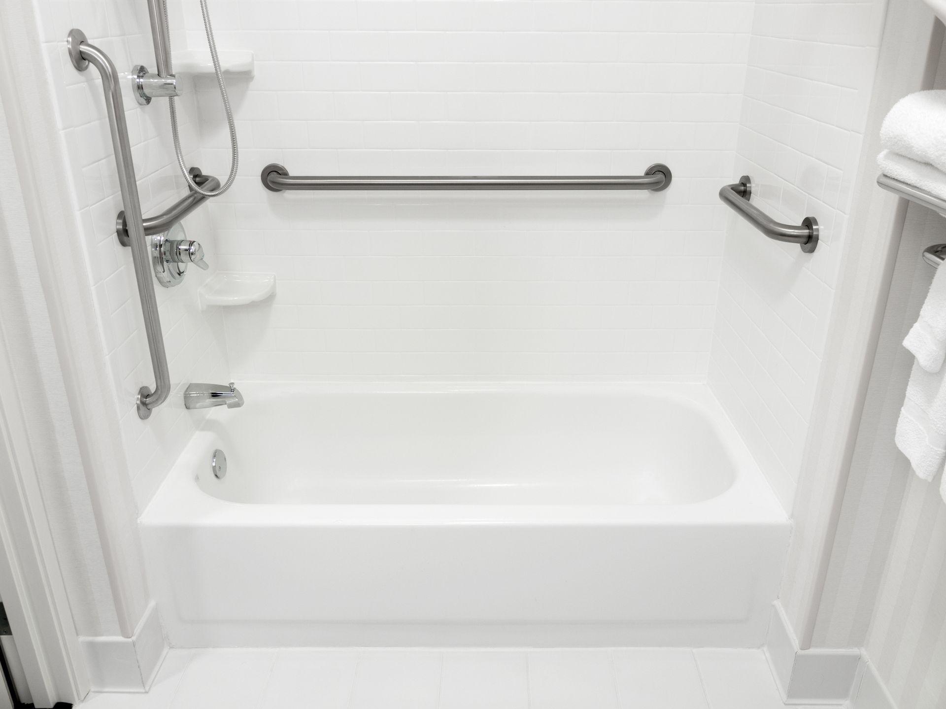 White bathtub with grab bars for accessibility.