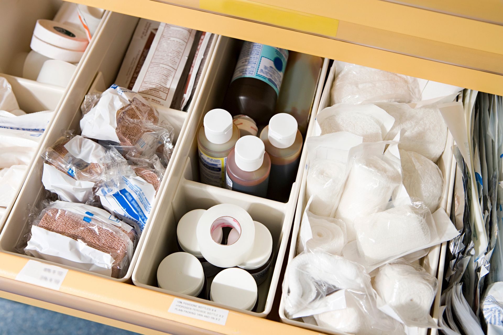 Drawer filled with medical supplies: bandages, tape, bottles, and cotton balls.
