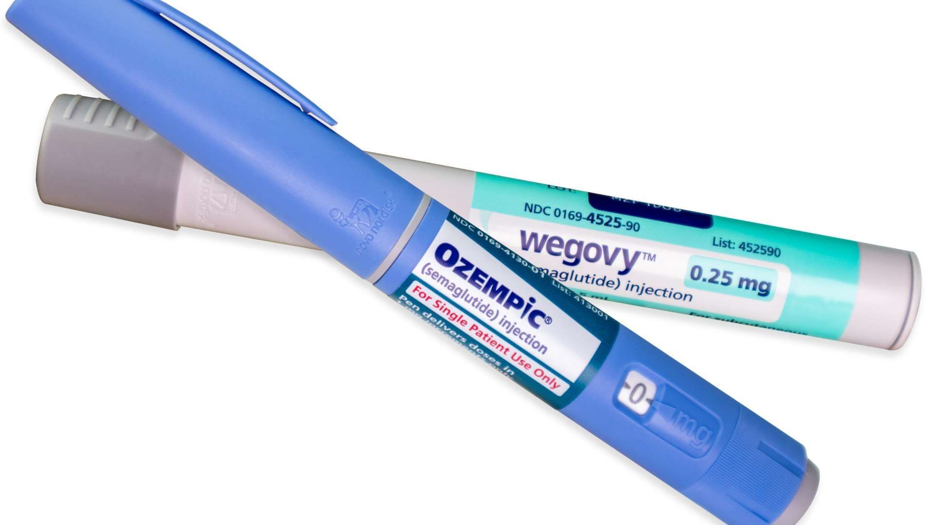 Two Wegovy and Ozempic injection pens crossed on a white background.
