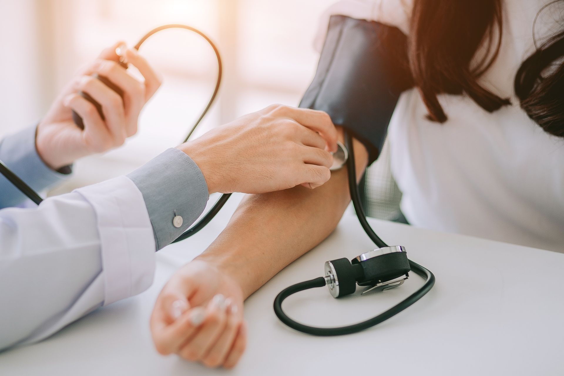 Doctor checking a patient’s blood pressure with a cuff and stethoscope in a clinic setting