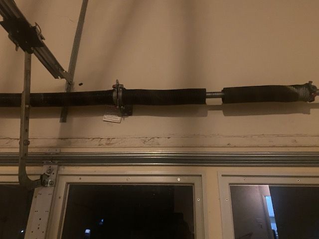 Black pipe runs along a wall above two windows in a dim indoor room.