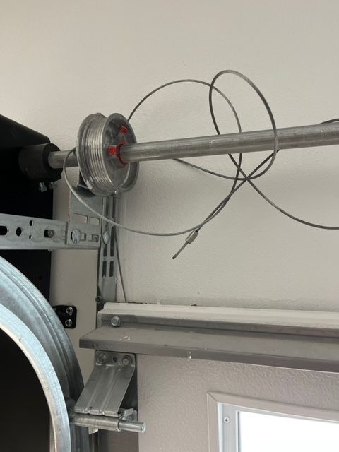 Garage door opener motor with loose coiled cable near the ceiling and a window below.