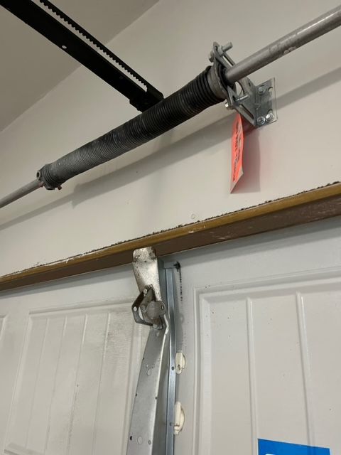 Damaged garage door with broken opener arm hanging from the top track