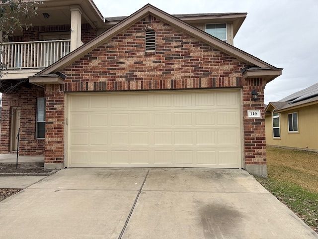 Brick house front with beige two-car garage and driveway
