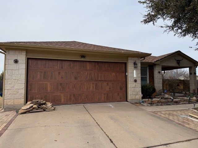 Suburban house with a large wooden garage door and sloped driveway under a cloudy sky
