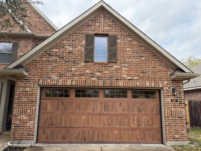 Brick house with a wooden two-car garage door and a small window above it