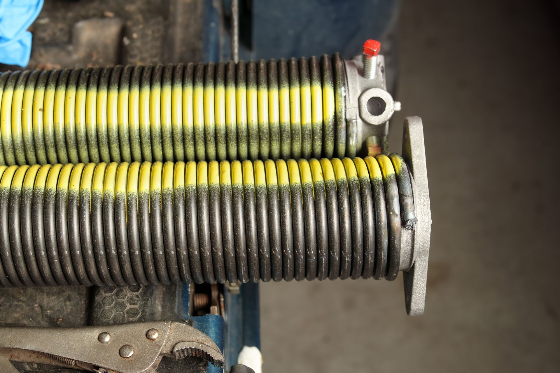 Two stacked coiled springs or hoses, one yellow-black and one gray, mounted on a metal mechanism.