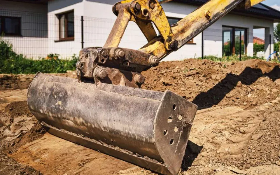 Yellow excavator bucket digging dirt at a construction site