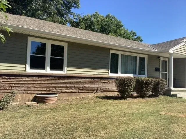 A house with a lot of windows and a large lawn in front of it.