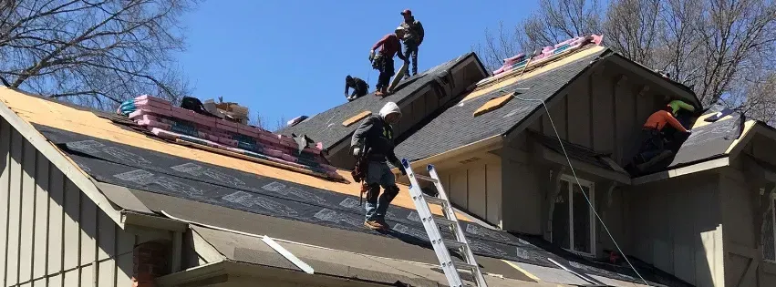 A group of people are working on the roof of a house.