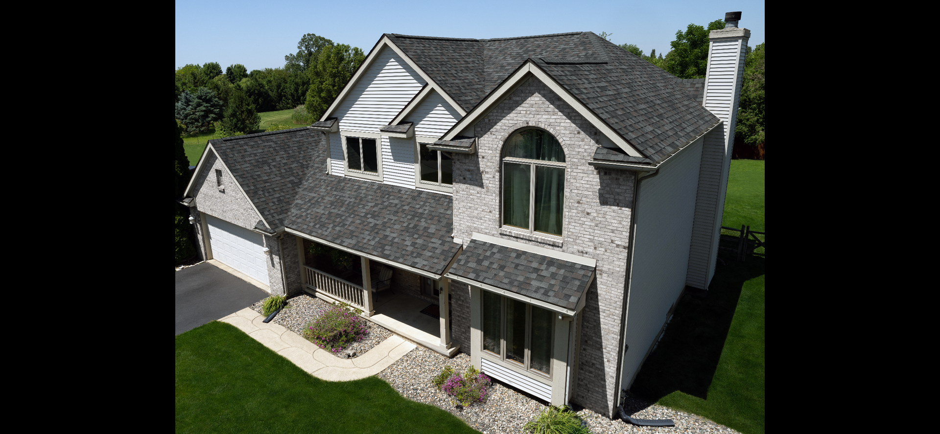 An aerial view of a large brick house with a gray roof.