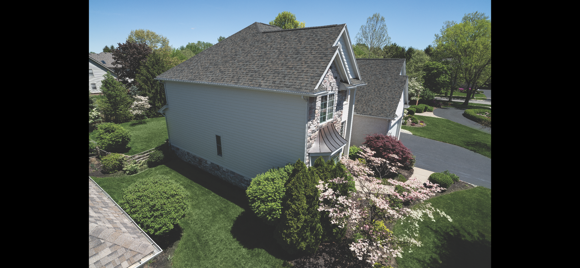 An aerial view of a white house with a gray roof in a residential area.