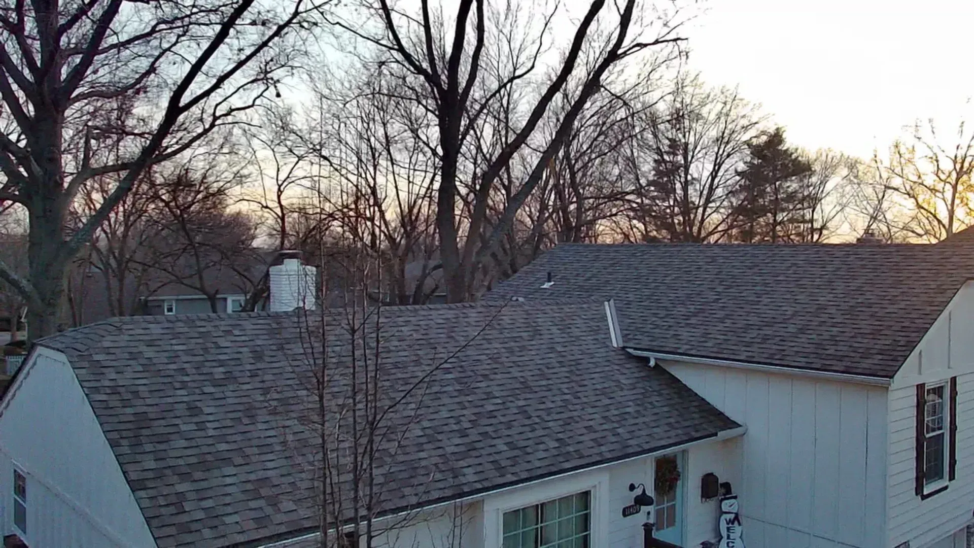 An aerial view of a house with a roof and trees in the background.