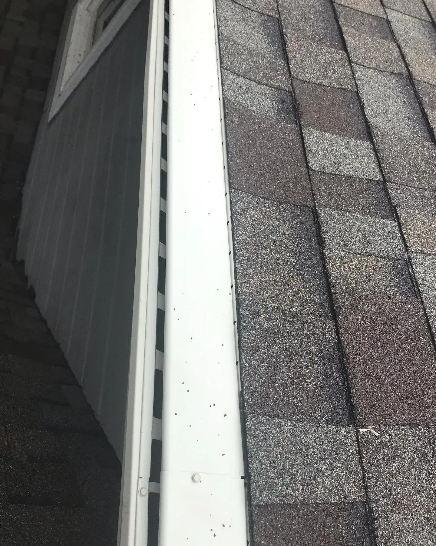 A close up of a gutter on a roof next to a window