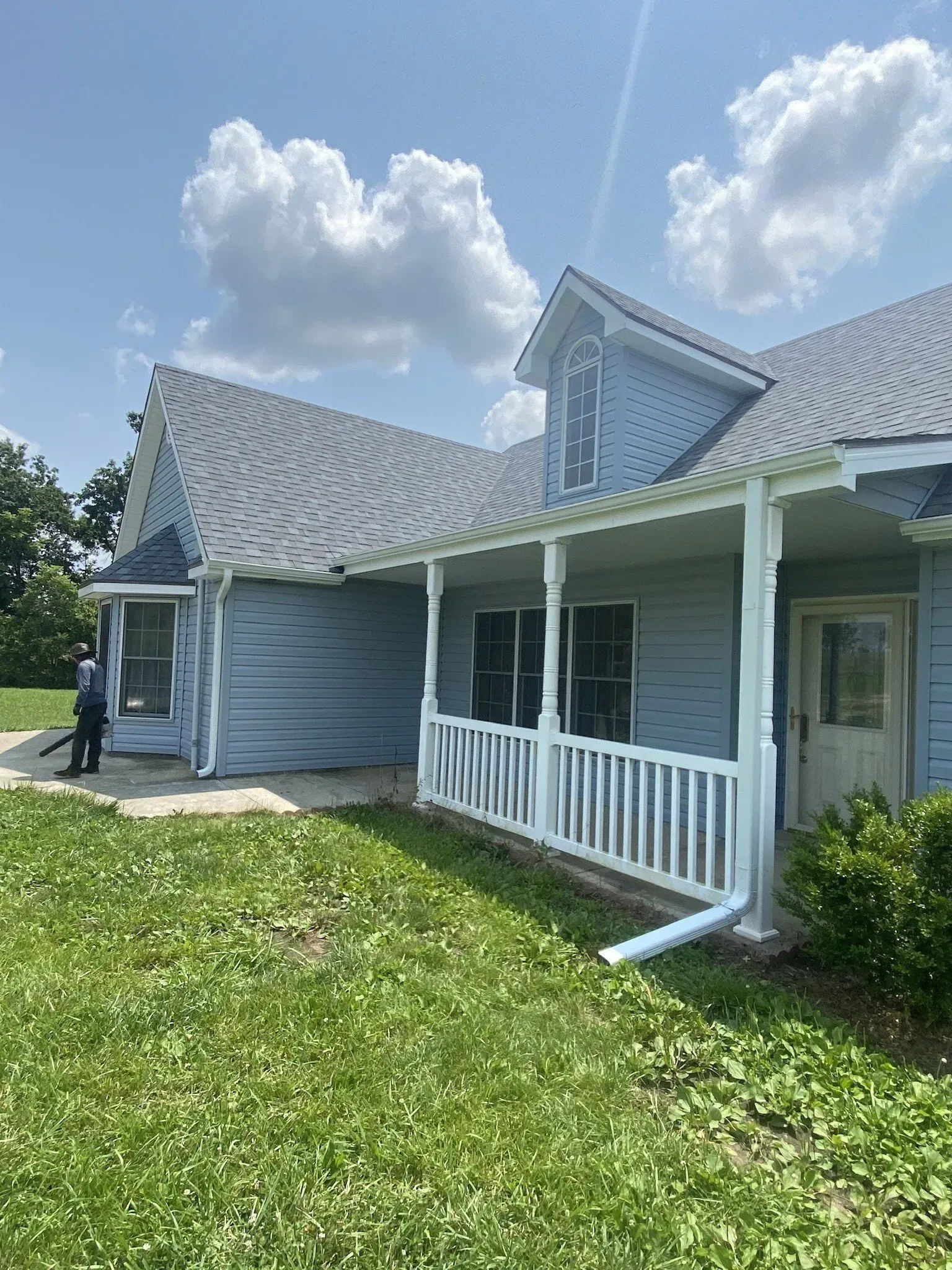 A blue house with a white porch and a gray roof.