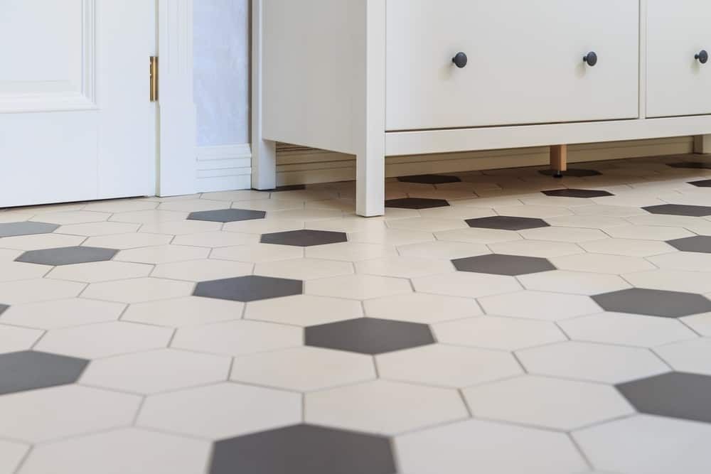 White and gray hexagon tile floor, white cabinet, door partially visible.