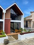 Two-story modern home with large windows, brown and white facade, and small garden.