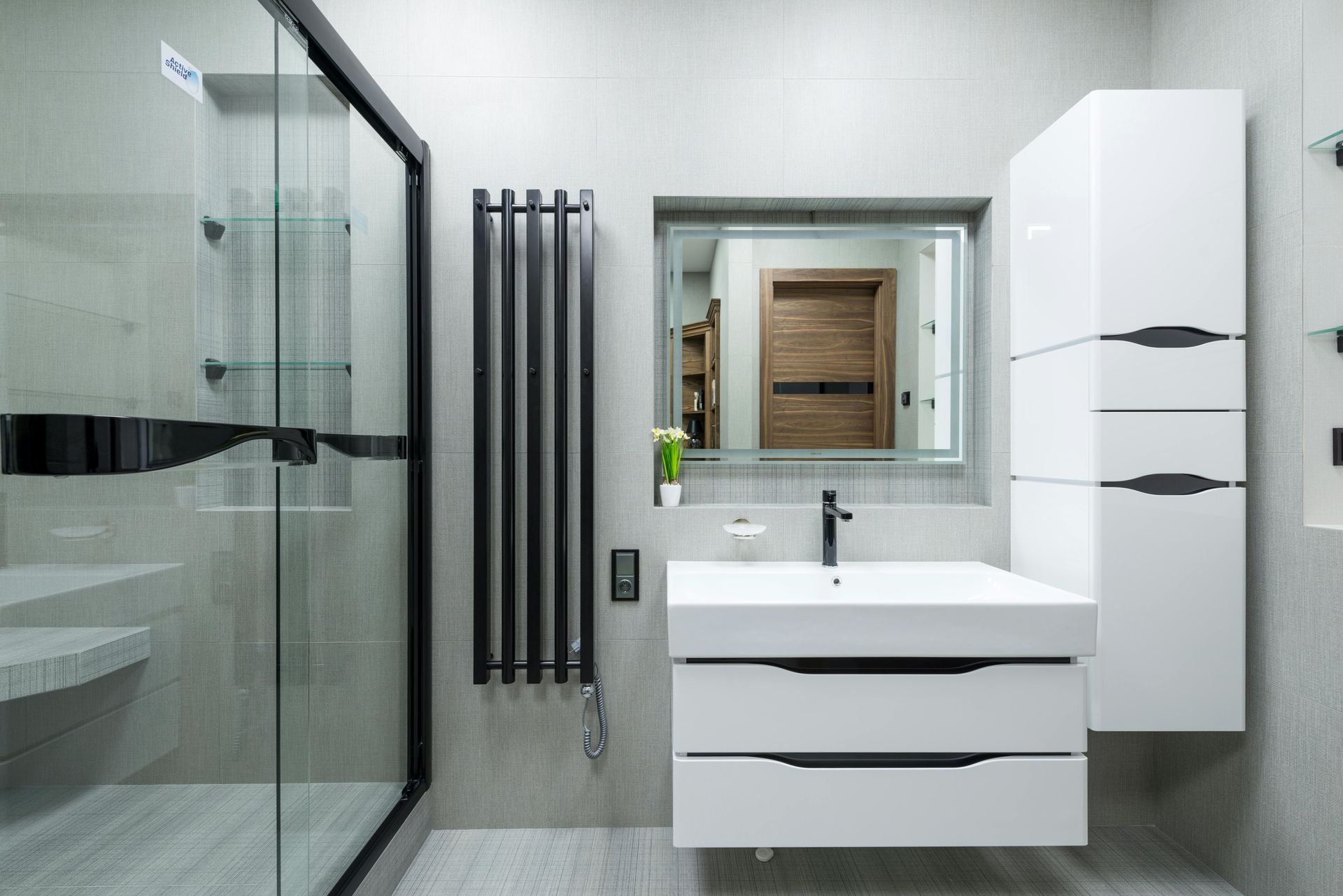 Modern white bathroom with glass shower, floating vanity, tall storage cabinet, and gray accent wall.