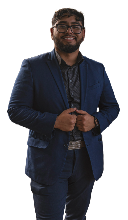 A man in a blue suit and glasses is standing in front of a white background.