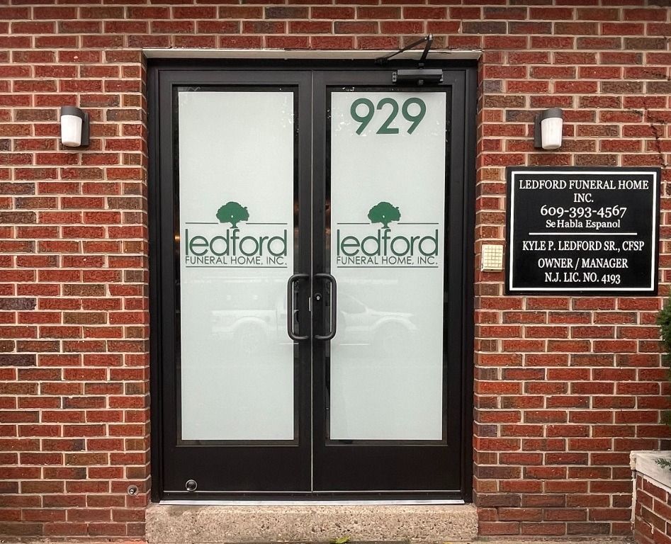 The entrance to Ledford Funeral Home with brick walls, frosted glass double doors, and an informational sign.