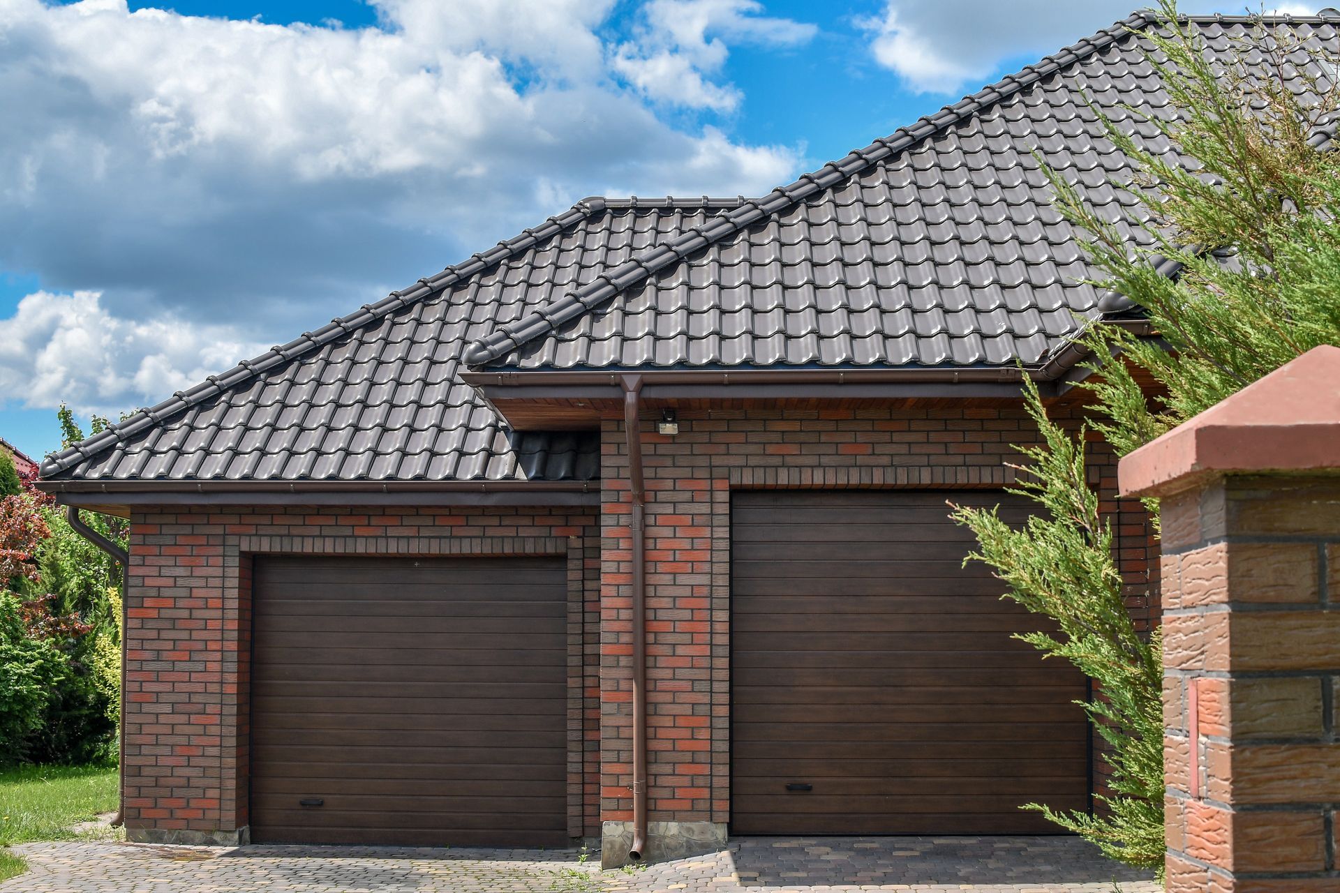 Double roller doors of a garage with a short driveway.