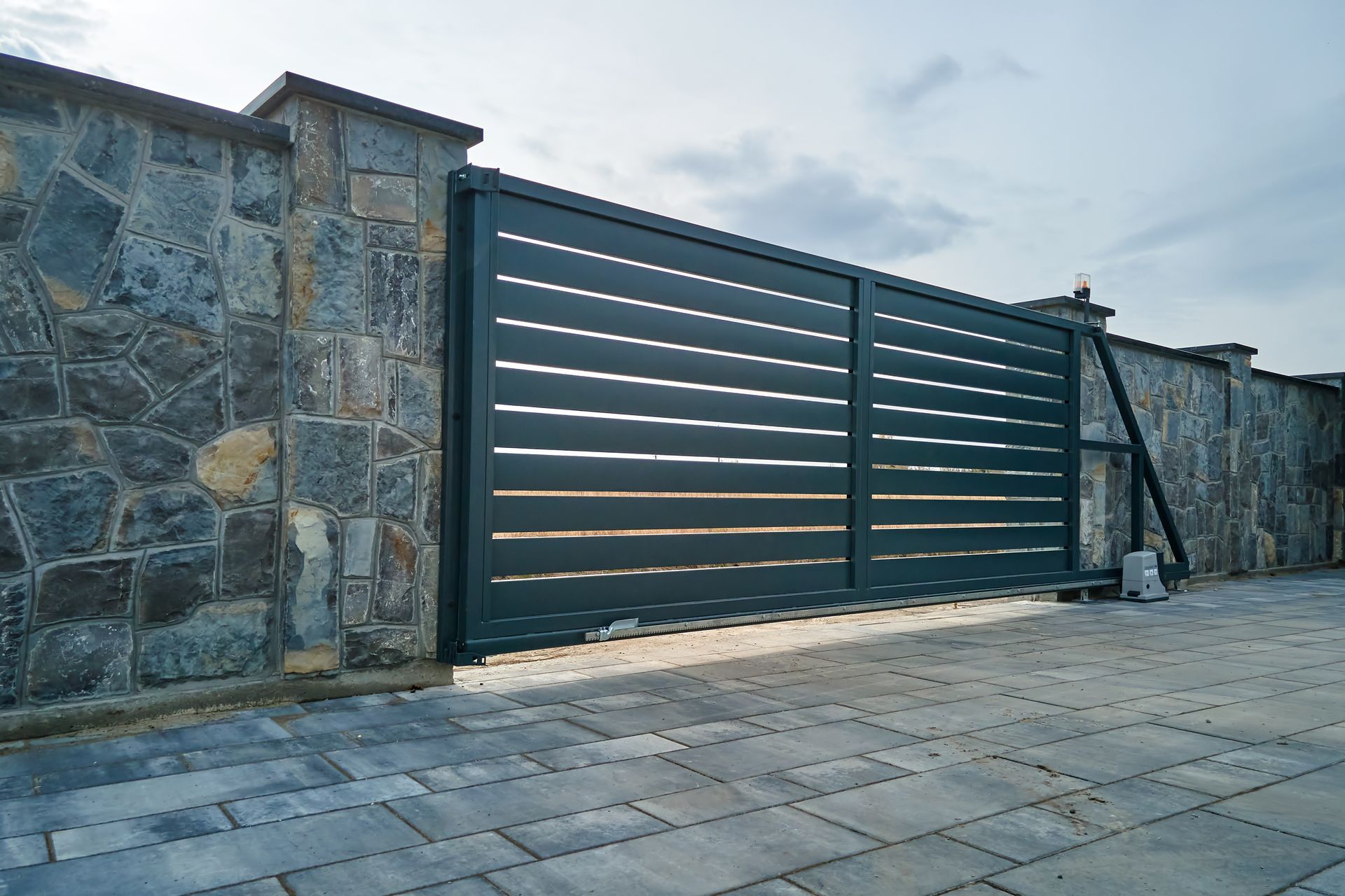 Inside view of an electric garage door made out of metal and with a stone fence around it.