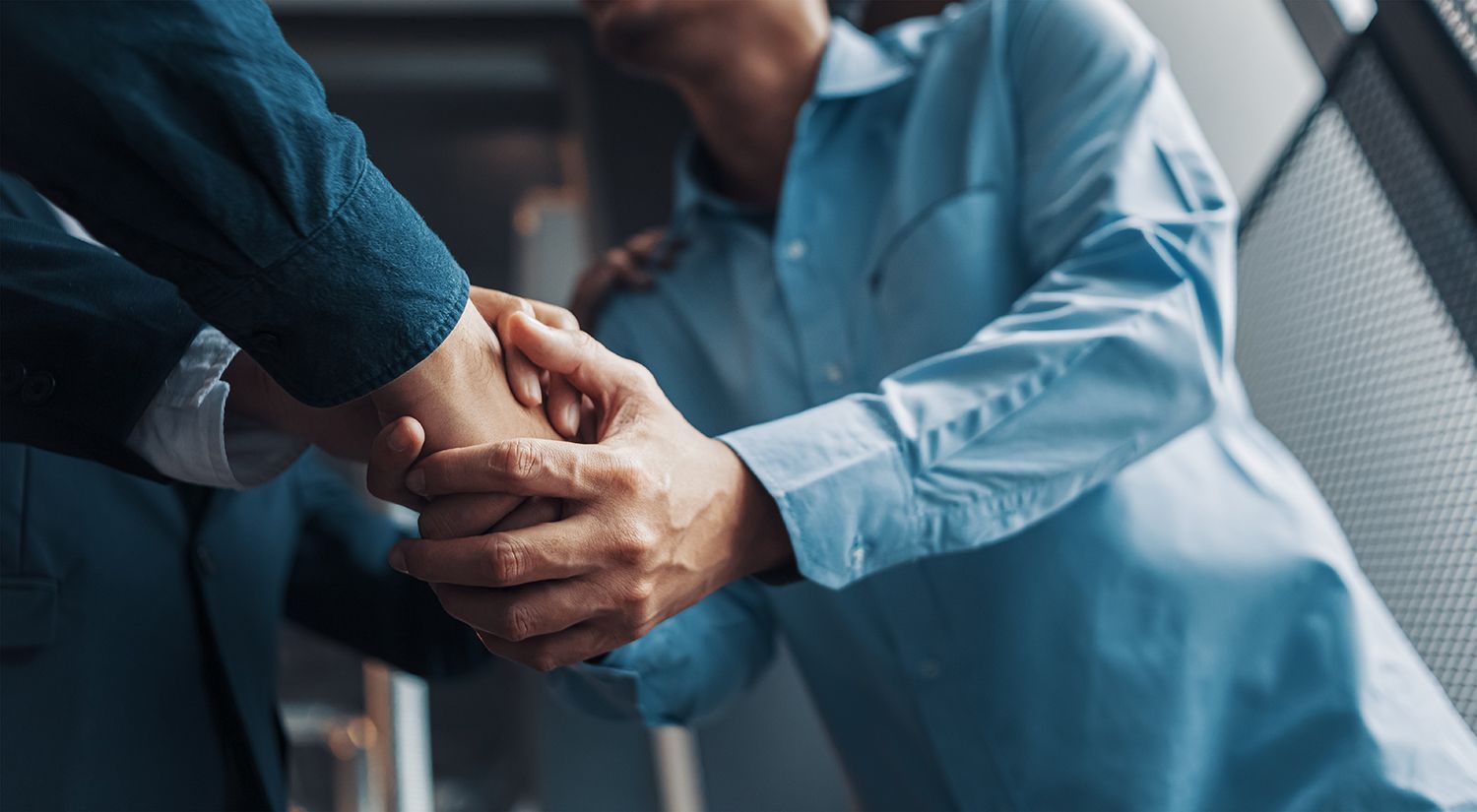 Two people in blue shirts shaking hands in a professional setting