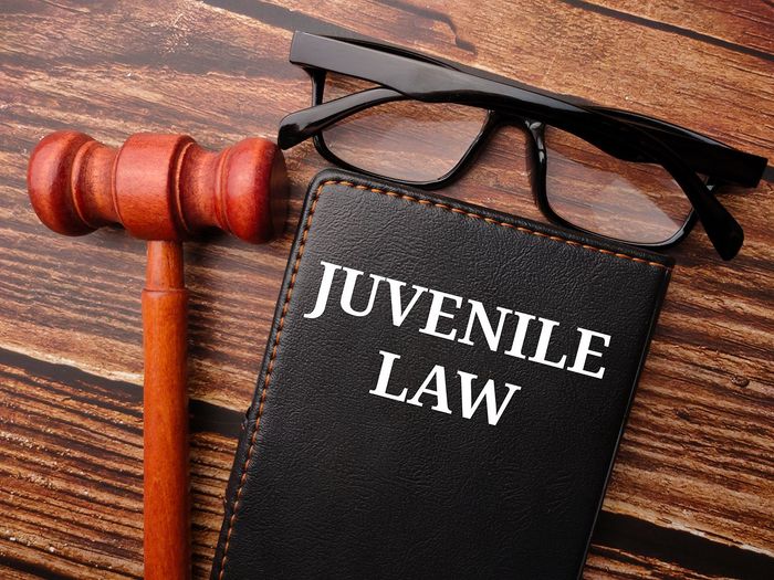Juvenile law book beside a gavel and eyeglasses on a wooden desk
