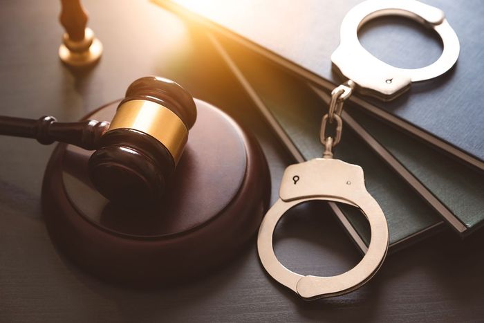Judge’s gavel beside handcuffs on a desk, symbolizing criminal justice and arrest