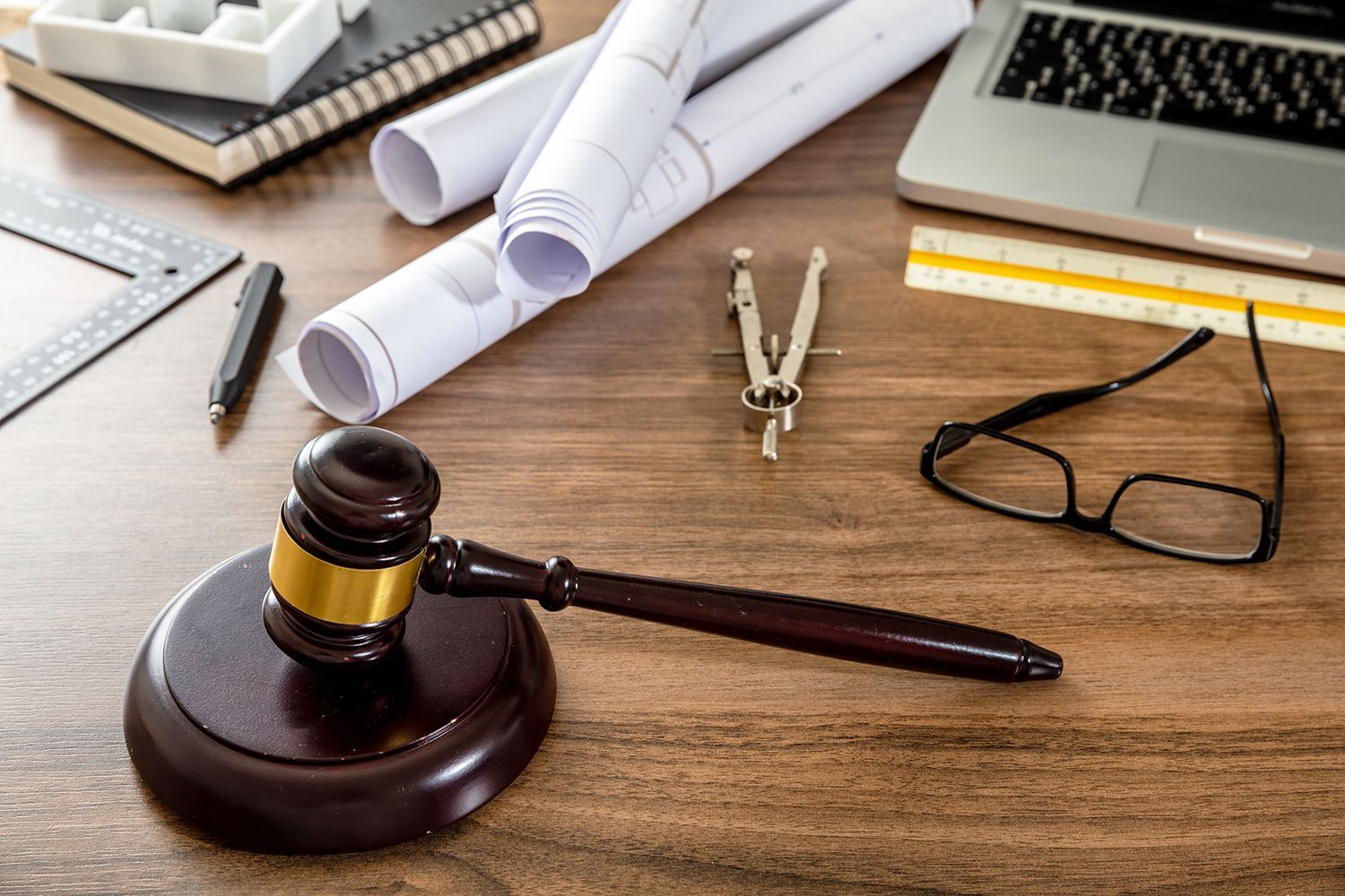 Lawyer’s desk with gavel, rolled documents, glasses, and office supplies Lawyer’s desk with gavel, rolled documents, glasses, and office supplies