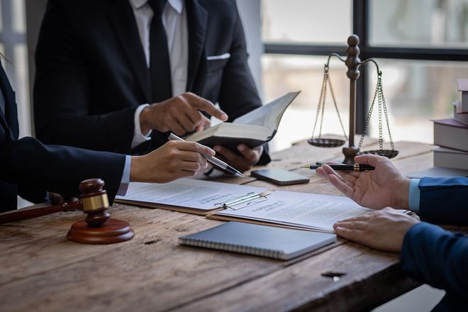 Lawyers reviewing documents at a desk with a gavel and scales of justice