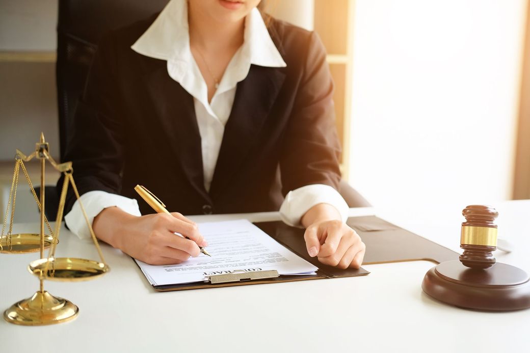 Two people reach for a handshake over a desk with a pen and paperwork.