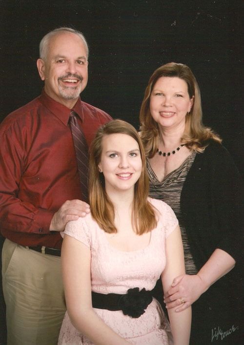 Three people pose in a studio portrait against a black background.