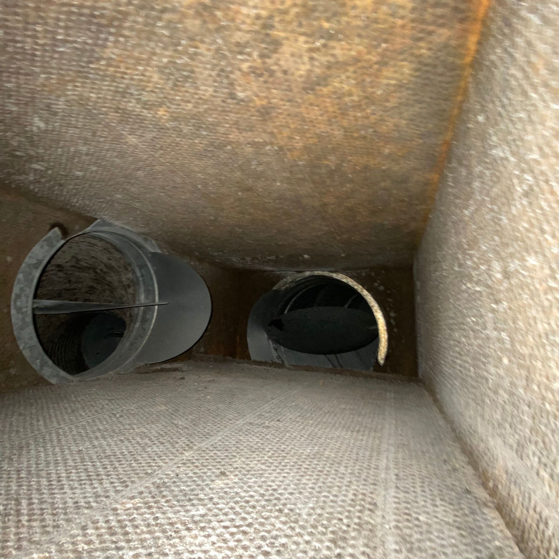 A tunnel with two pipes going through it and a brick wall.