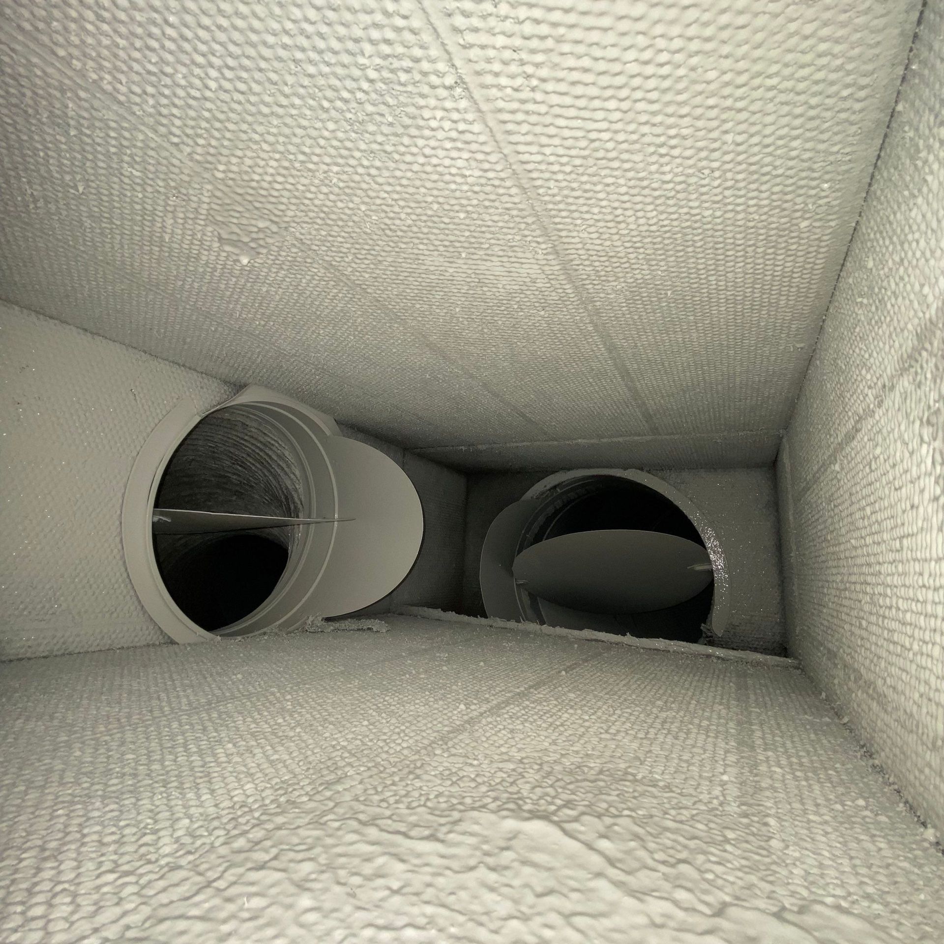 A black and white photo of a tunnel with pipes going through it.