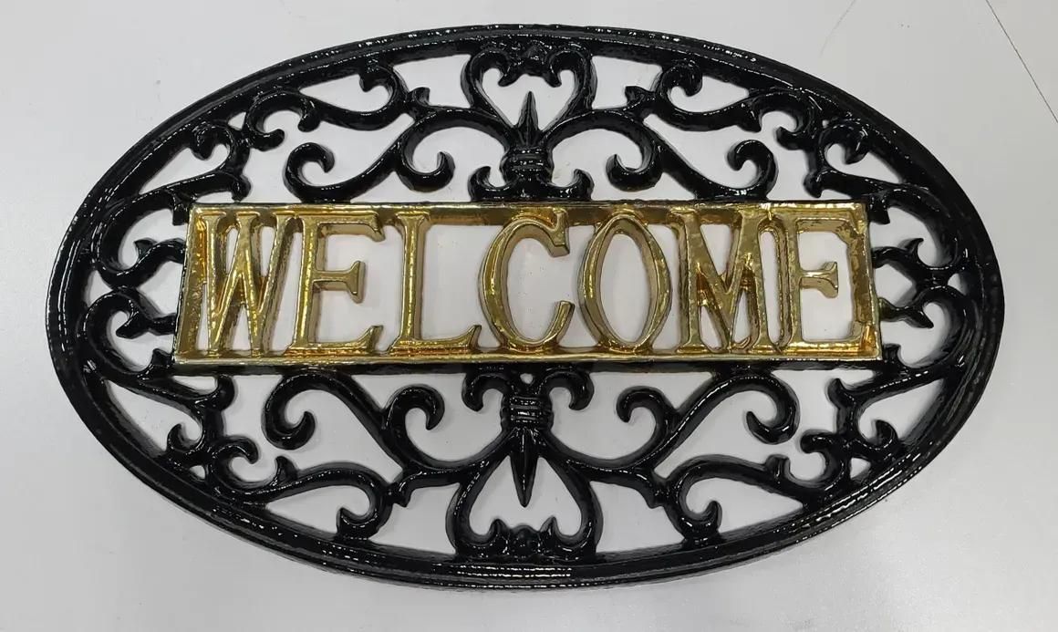 An oval, black metal decorative sign featuring an ornate scrollwork border.